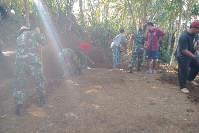 Anggota TNI bersama masyarakat melaksanakan gotong royong